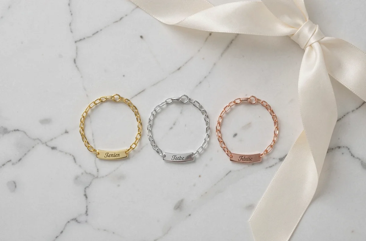 Trois gourmettes enfant en or jaune, or blanc et or rose disposées côte à côte sur un marbre blanc, vue de dessus
